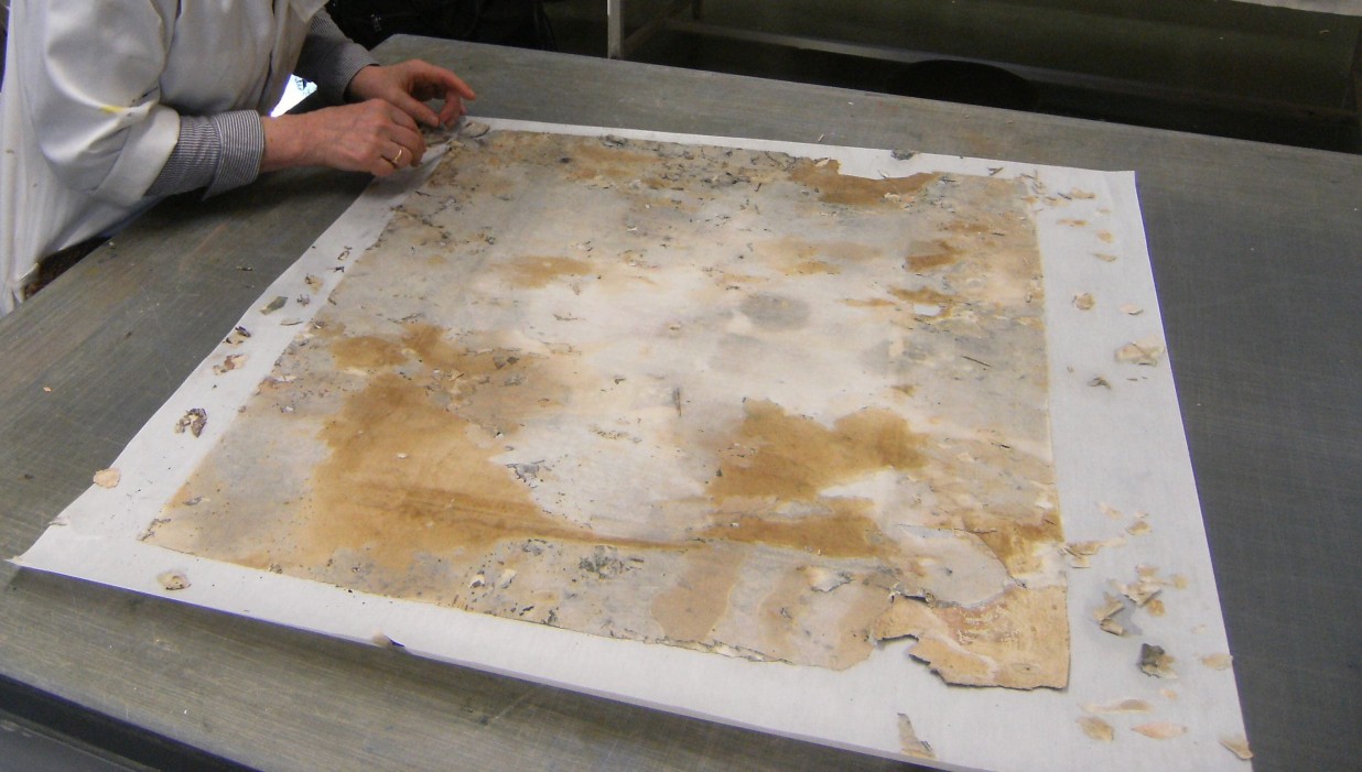 Personne en train de restaurer une carte ancienne abîmée.